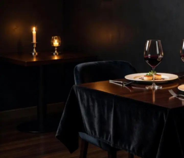Mesa de cena privada iluminada con luz cálida en un salón oscuro y elegante
